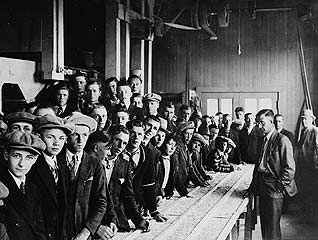 Photo of Group of people around a grain-cleaning table, ca. 1910