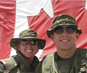 Two members of the Canadian Forces in front of a flag.