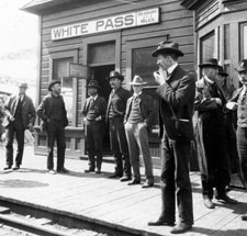 Klondike Gold Rush National Historic Park, Alaska. Passengers, gathered outside the White Pass & Yukon Railroad Station at White Pass. The photographer on one of the expeditions, Sidney Paige, is in the centre in the white hat. Circa 1900 