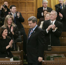 Stephen Harper is given a standing ovation from caucus members after voting for his no-confidence motion in the House of Commons. (CP photo)