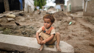 A child sits amid the ruins of his family's house in the flood-ravaged town of Adiel Khan in Pakistan's northwest Khyber-Pakhtunkhwa province on Thursday.  