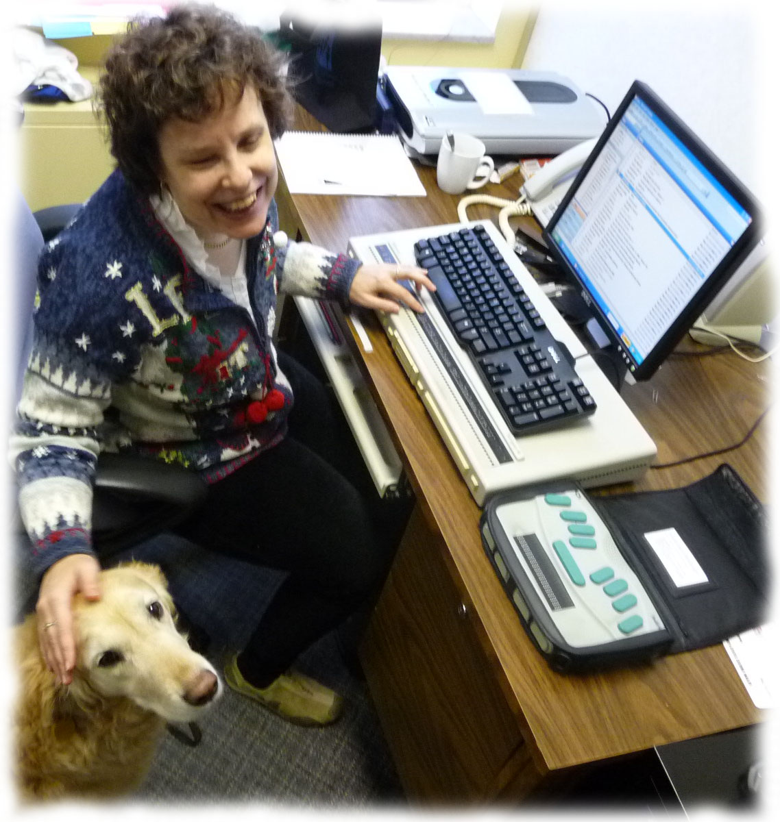 Kim working at her desk with her guide dog