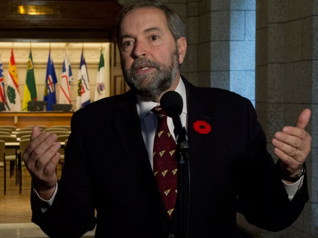 With the doors to a caucus room wide open, NDP leader Tom Mulcair speaks with reporters on Parliament Hill Wednesday October 29, 2014 in Ottawa. 
