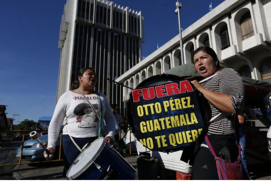 Protesters drum outside the court in Guatemala City where former president Otto Perez Molina is expected to arrive to face corruption charges following his overnight resignation, on Thursday, Sept. 3. The sign reads, "Get out Otto Perez, Guatemala doesn't want you."
