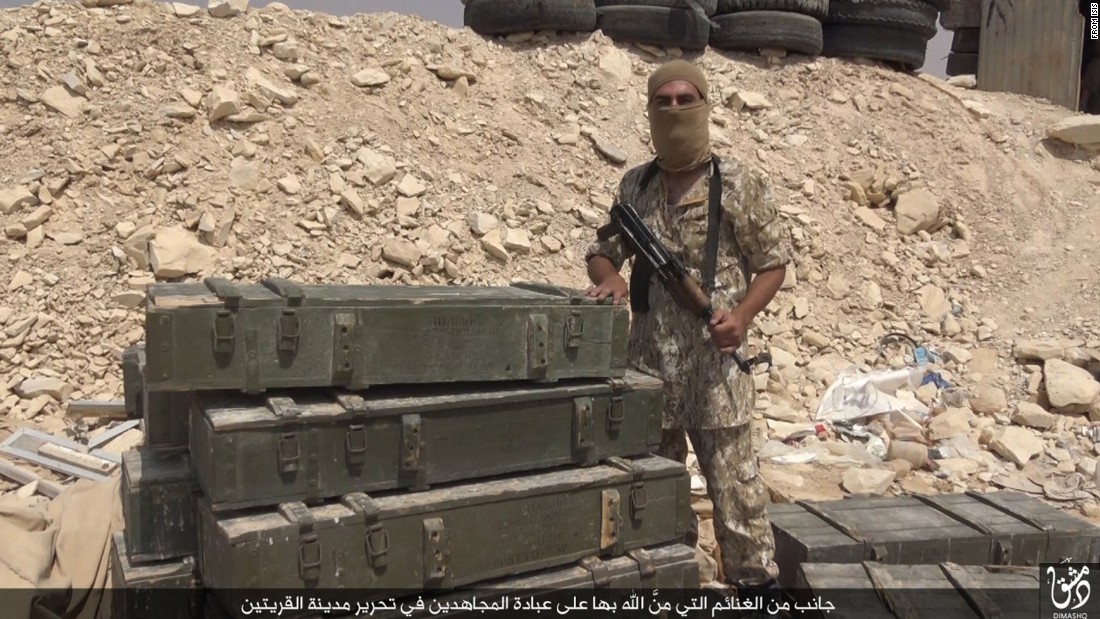 An ISIS fighter poses with spoils purportedly taken after capturing the Syrian town.
