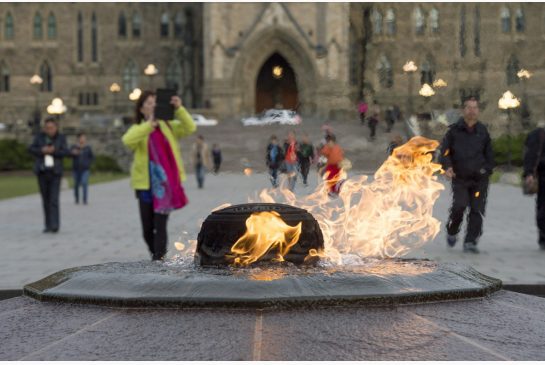 Visitors walk past the Centennial Flame on Parliament Hill in Ottawa on Saturday. The grounds and lawn of Parliament Hill reopened Friday night following the shootings at the National War Memorial and inside Centre Block.
