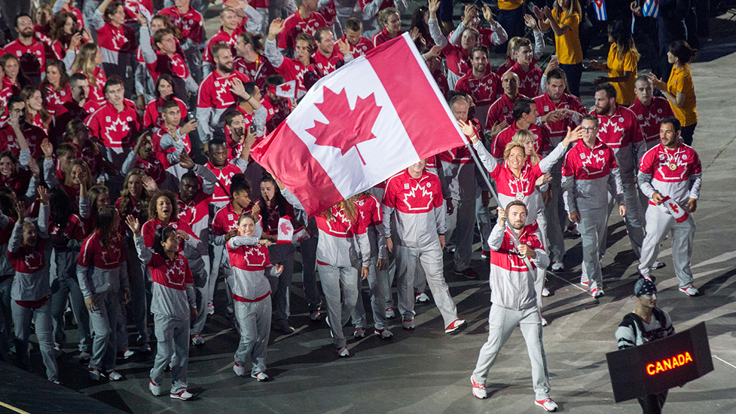 Mark Oldershaw agite le drapeau canadien à l'entrée d'Équipe Canada dans le stade du Centre Rogers pendant la cérémonie d'ouverture des Jeux panaméricains de 2015.