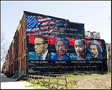 A painted mural shows the faces of Malcolm X, Ella Baker, Martin Luther King Jr., and Frederick Douglass