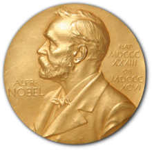 A golden medallion with an embossed image of Alfred Nobel facing left in profile. To the left of the man is the text "ALFR•" then "NOBEL", and on the right, the text (smaller) "NAT•" then "MDCCCXXXIII" above, followed by (smaller) "OB•" then "MDCCCXCVI" below.