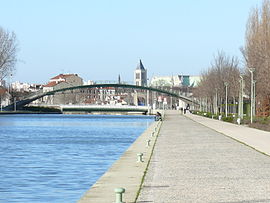 The Canal Saint-Denis with swing bridge, pedestrian overpass leading to the Stade de France and the Basilique Saint-Denis in the background.