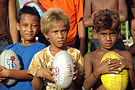 A close up shot of three junior AFL player holding footballs at the Lord Howe Settlement, Honiara. (10661462334).jpg