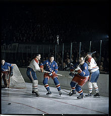 Five men playing hockey in a crowded arena.