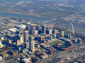 An aerial view of many skyscrapers and other buildings, with a dark blue river cutting down through the upper half.