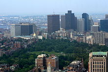 City skyline with a body of water in the background and a green park in the foreground