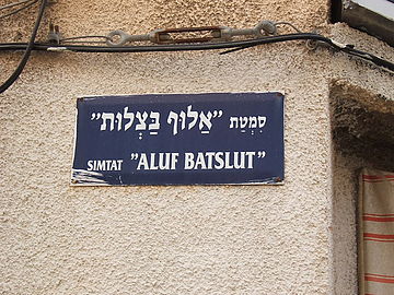 Hebrew street sign, above in Hebrew alphabet, below in Latin transliteration. Aluf Batslut veAluf Shum(he) ("The Knight of Onions and the Knight of Garlic") is a story by Hayim Nahman Bialik.