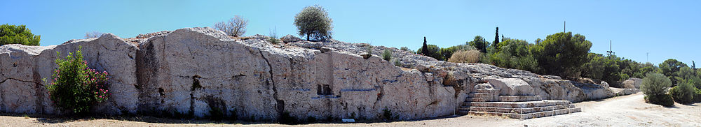 Panorama of the Pnyx, showing the wall with indentations from now-gone wooden beams and the carved steps on the right-hand side.