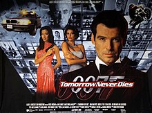 A man wearing evening dress holds a gun. On his sides are a white woman in a white dress and an Asian woman in a red, sparkling dress holding a gun. On the background are monitors with scenes of the film, with two at the top showing a man wearing glasses holding a baton. On the bottom of the screen are two images of the 007 logo under the title "Tomorrow Never Dies" and the film credits.