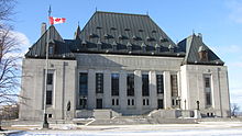 Large grey building in winter, with a Canadian flag in front