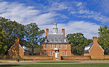 A three-story red brick colonial style hall and its left and right wings during summer.