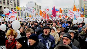 alt = A crowd of enthusiastic protesters on Academician Sakharov Avenue, Moscow. Many balloons, posters, and flags. The protesters are bundled up on a cold overcast Winter day.