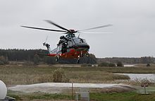 Huey helicopter landing on a pad next to a wetland