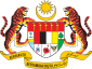Shield showing symbols of the Malaysian states with a star and crescent above it and a motto below it supported by two tigers