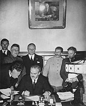 Soviet Foreign Minister Vyacheslav Molotov signs the Molotov-Ribbentrop Pact. Behind him stand German Foreign Minister Joachim von Ribbentrop and Soviet Premier Joseph Stalin.