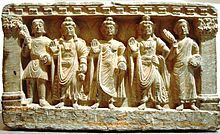 stone statue group, a Buddhist triad depicting, left to right, a Kushan, the future buddha Maitreya, Gautama Buddha, the bodhisattva Avalokiteśvara, and a Buddhist monk. 2nd—3rd century. Guimet Museum