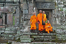 monks in orange robes on stone steps in Cambodia