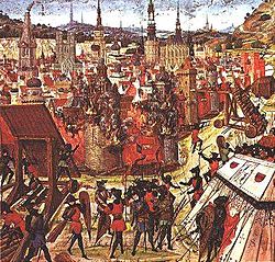 alt=A depiction of the capture  of Jerusalem in 1099 from a medieval manuscript. The burning buildings of Jerusalem are centered in the image. The various crusaders are surrounding and besieging the village armed for an attack.