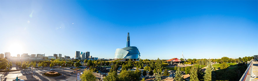 Panorama of The Canadian Museum for Human Rights against a blue sky, light flare from the bright sun visible in the left corner.