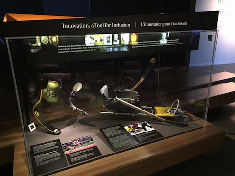 Display cases showing prosthetic arm and running foot, and a hockey sledge.