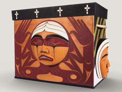A carved wooden box with the image of an agonized face.