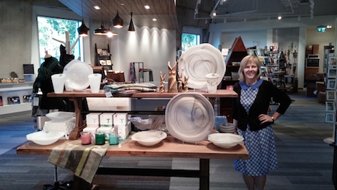 A woman stands beside a display table in the Museum’s Boutique.