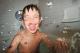 A boy splashes water in the bathtub.