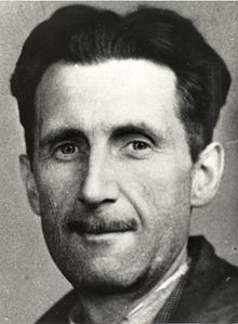 A photo showing the head and shoulders of a middle-aged man with black hair and a slim moustache.