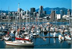 This photograph shows small boats in a marina with downtown Vancouver in the background.
