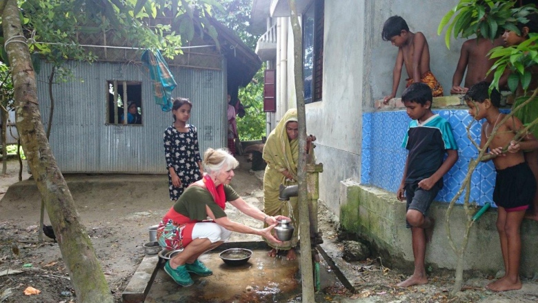 Judit collecting well water with villager