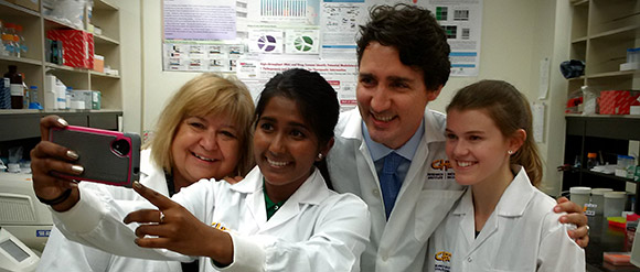 Le Premier Ministre Trudeau et la Ministre Mihychuk, Ministre de l’Emploi, du Développement de la main-d’œuvre et du Travail, prennent une photo avec deux étudiantes dans un laboratoire.
