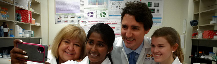 Le Premier Ministre Trudeau et la Ministre Mihychuk, Ministre de l’Emploi, du Développement de la main-d’œuvre et du Travail, prennent une photo avec deux étudiantes dans un laboratoire. 