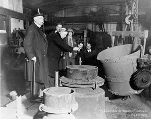 Le premier ministre Mackenzie King lance une pièce commémorative de dix cents dans le métal en fusion de la cloche. Croydon, Angleterre, 1926.