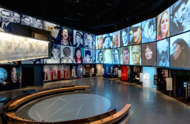 A large gallery with pictures of people shown on an overhead screen