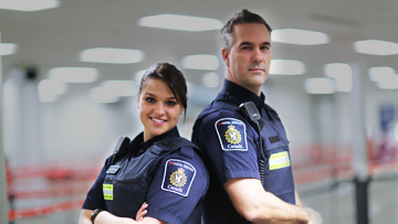A photo of two border services officers standing back-to-back.