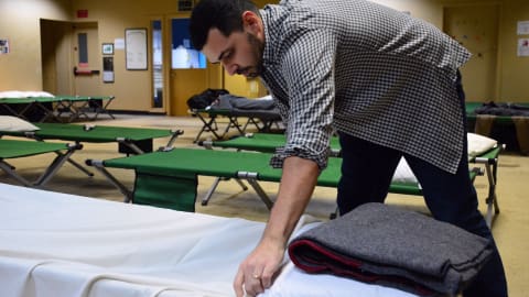 Justin Leblond, un infirmier de la Maison de réduction des méfaits de l'Association canadienne pour la santé mentale, prépare un lit au refuge Off the Street à Sudbury. Photo: Radio-Canada/Benjamin Aubé