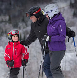 Deux adultes et un enfant font du ski