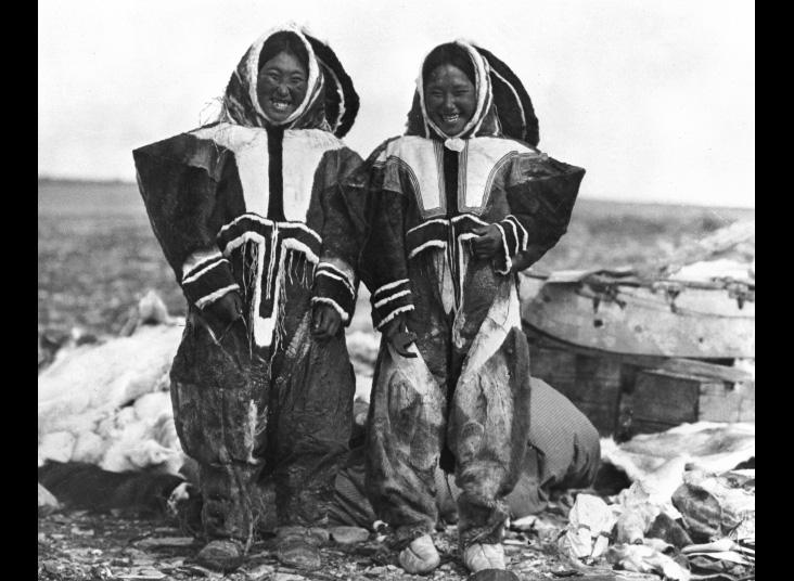 Two women stand in Inuit parkas.