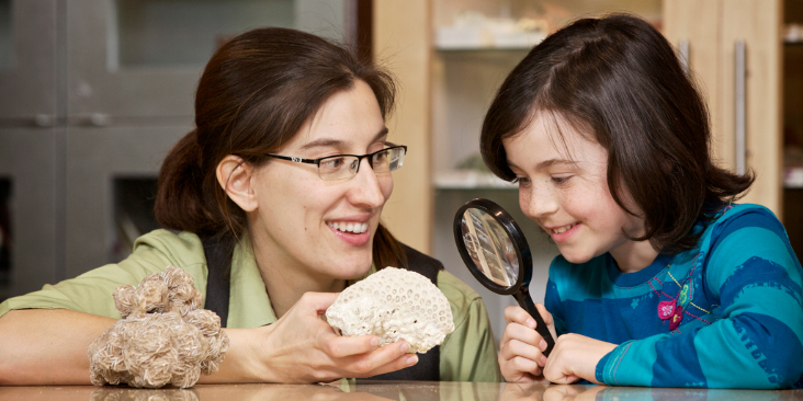 A girl and a museum staff member look at a coral specimen in Nature Trade.