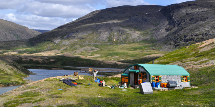 Text: Canada's Arctic Biodiversity: The Next 150 Years. Image: A cabin next to a river.