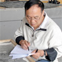 Xiao-Chun Wu consults some papers while sitting beside a fossil he is studying.