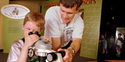 An educator and a child using a microscope.